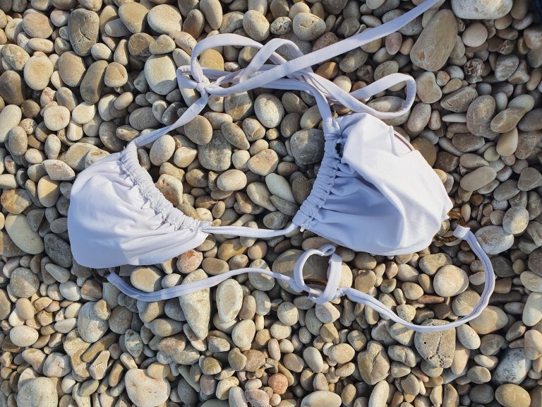 Selection of elegant swimsuits and bikinis styled on a beach for summer fashion inspiration